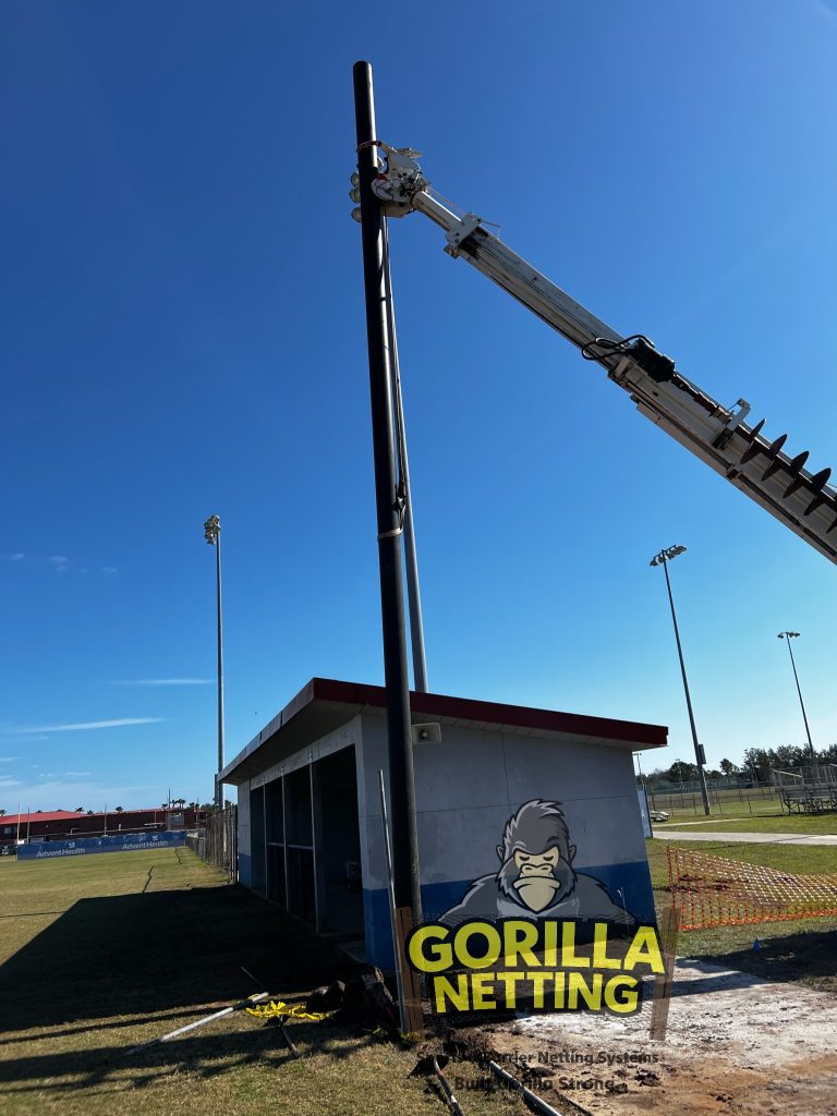 Poles being set for a baseball netting system.
