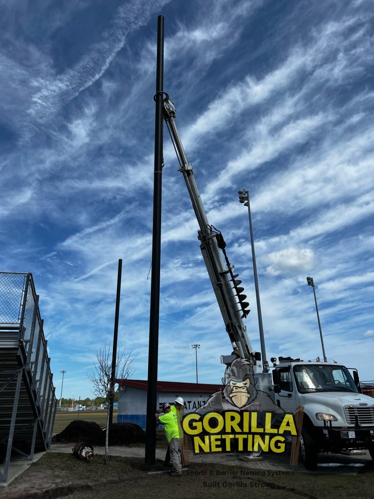 Poles being set for a baseball netting system.
