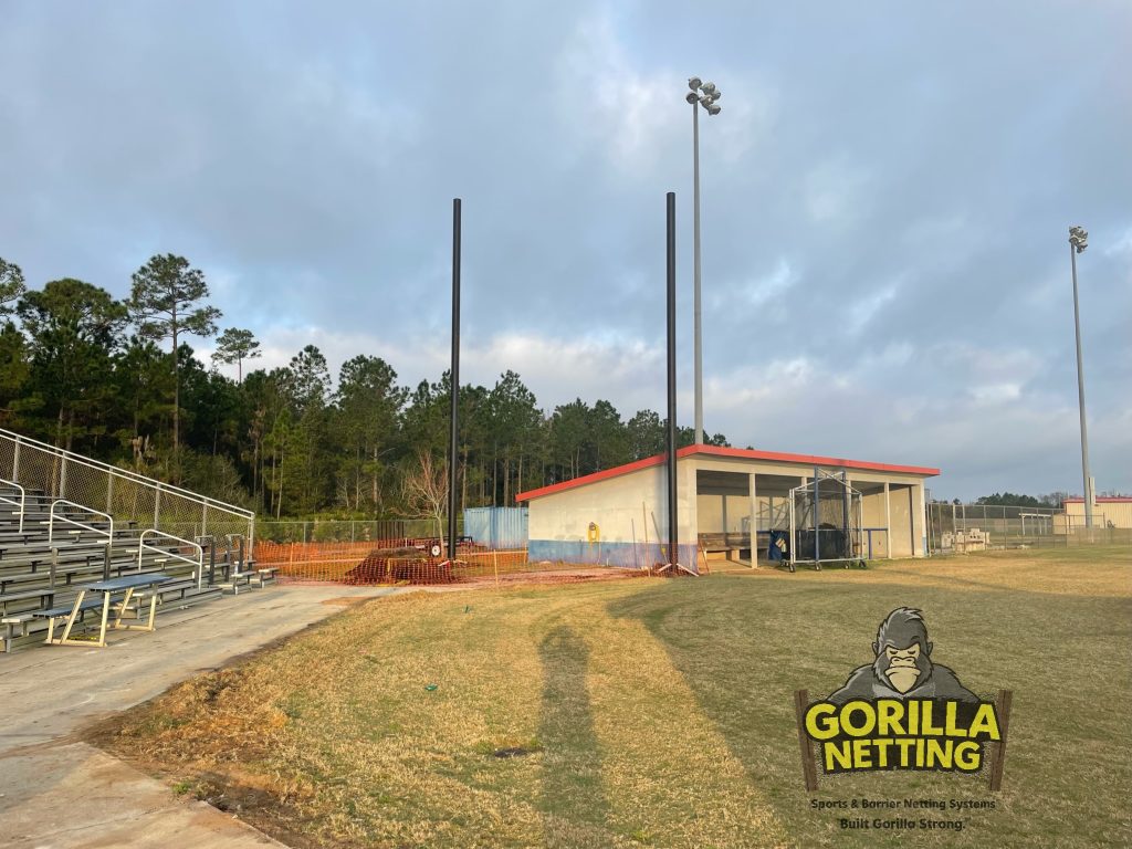 Poles being set for a baseball netting system.