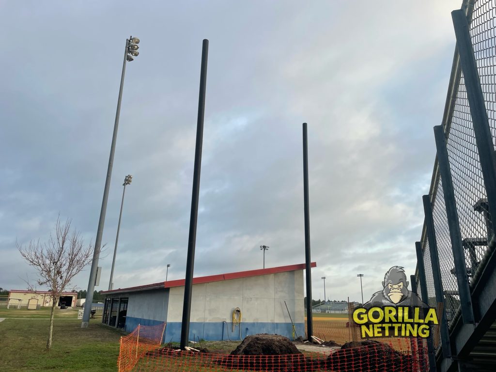 Poles being set for a baseball netting system.