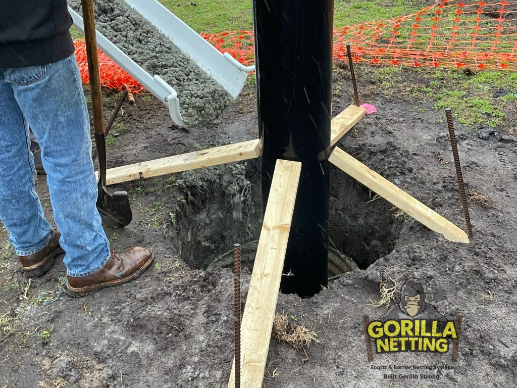 Poles being set for a baseball netting system.