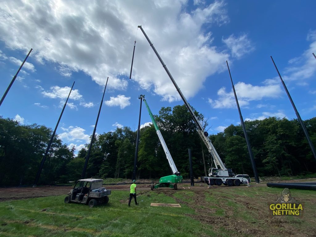 Staged poles installed for a driving range netting system.