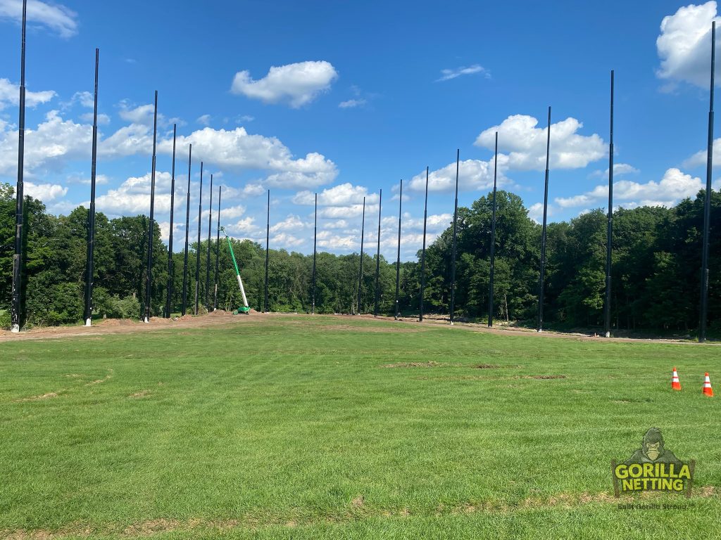 Staged poles installed for a driving range netting system.