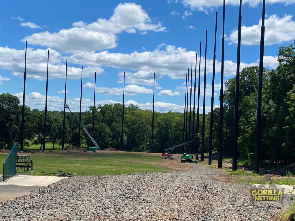Staged poles installed for a driving range netting system.