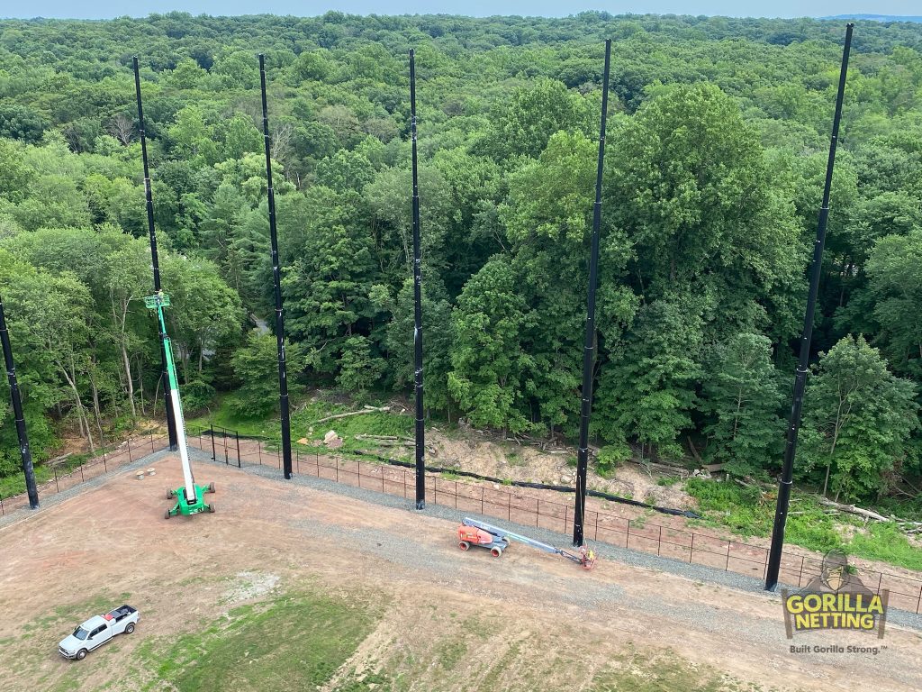 Staged poles installed for a driving range netting system.