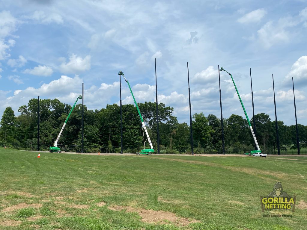 Staged poles installed for a driving range netting system.