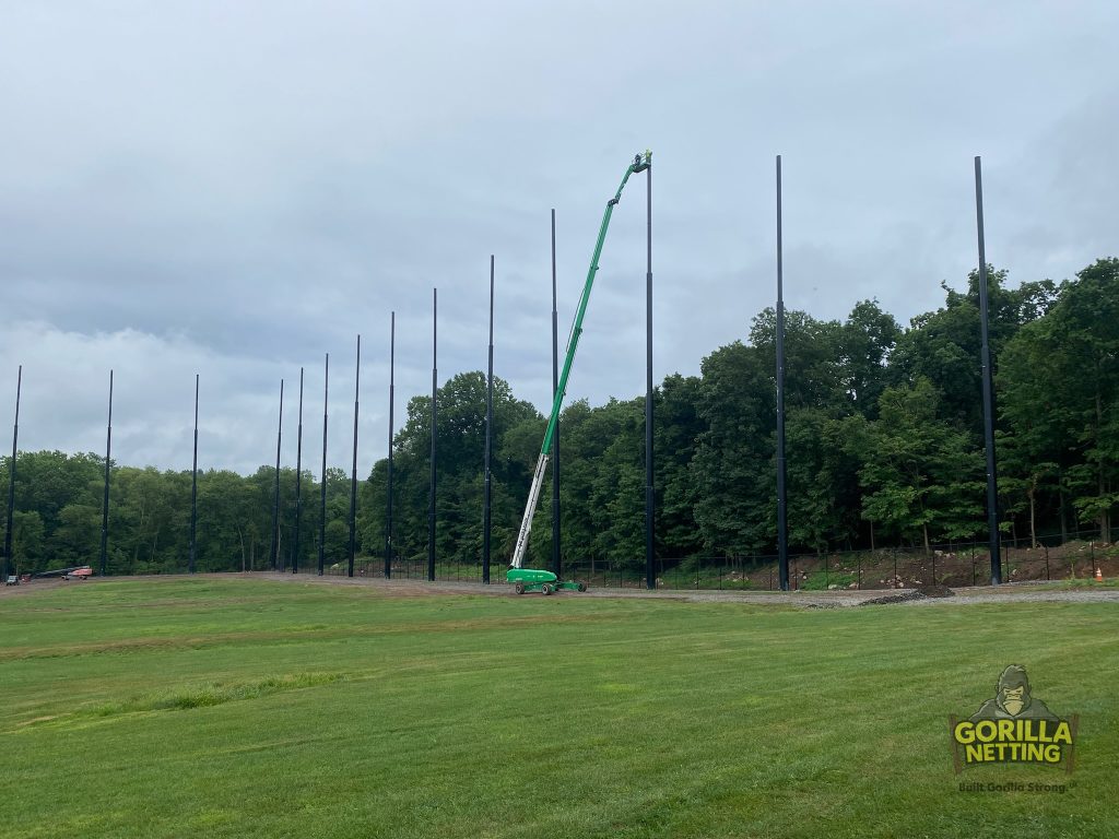 Staged poles installed for a driving range netting system.